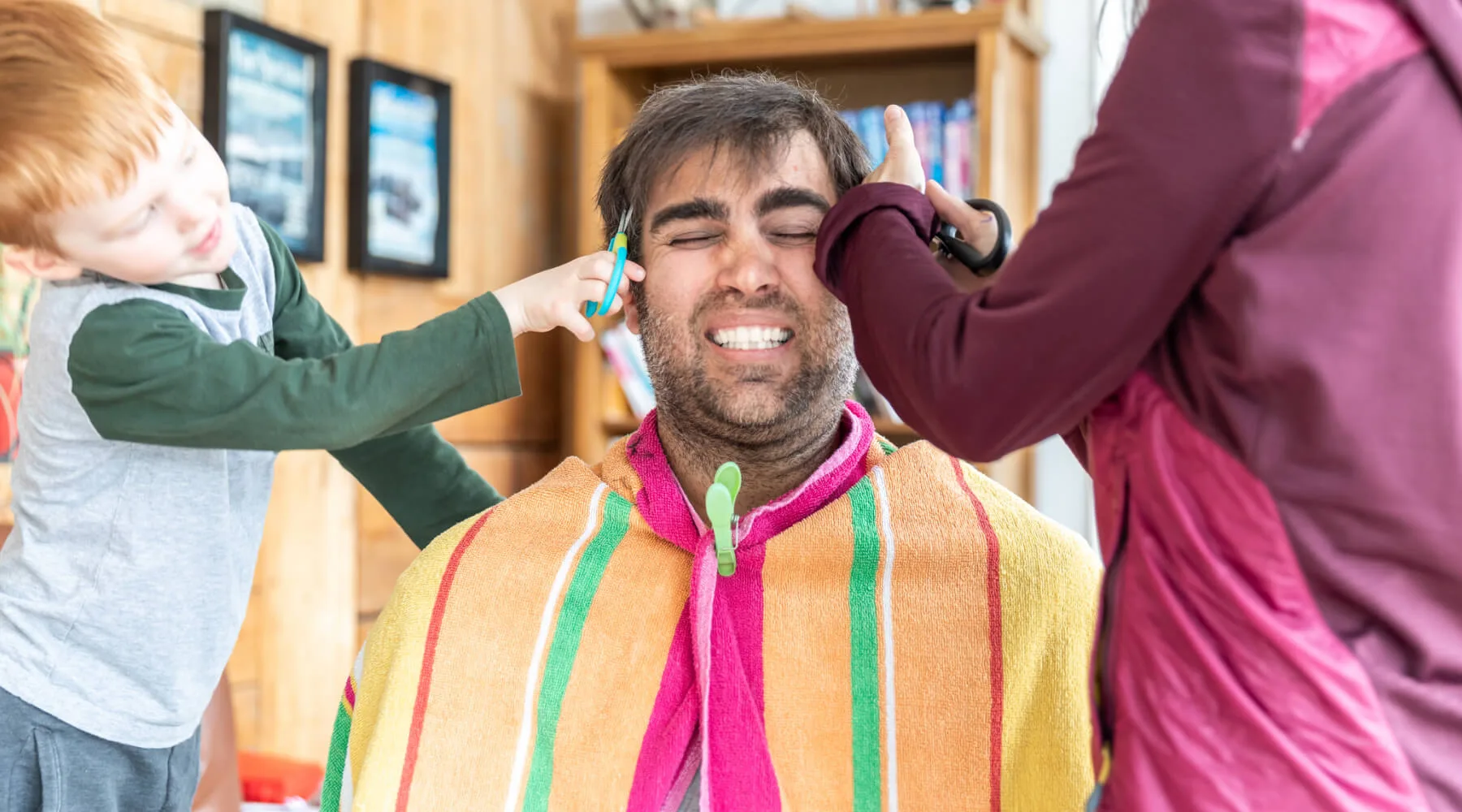 Mom and child giving dad a haircut